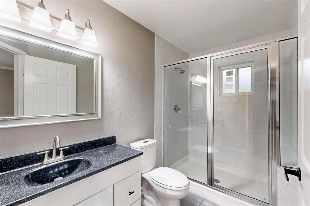 3264 Northaven Road Dallas, TX 75229 - Photo 18 of 35 Bathroom featuring a shower stall, vanity, toilet, and a textured wall
