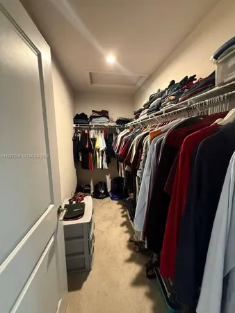 a view of walk in closet with clothes and shoes