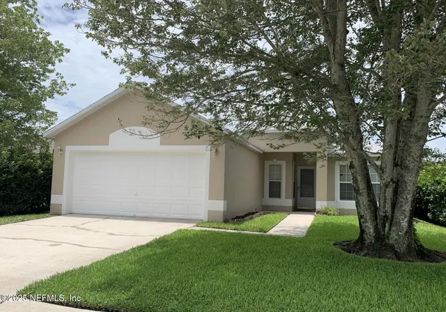 a front view of a house with a yard and large tree