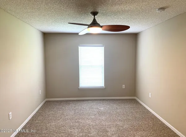 an empty room with a window and a chandelier fan