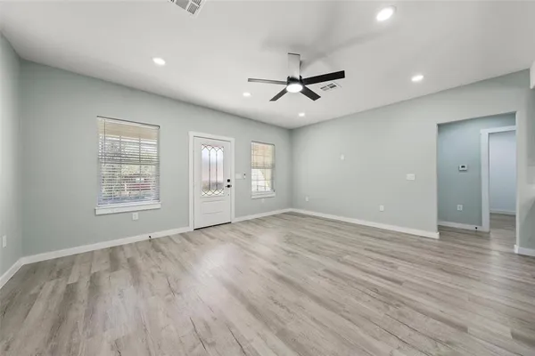 a view of an empty room with a window and wooden floor