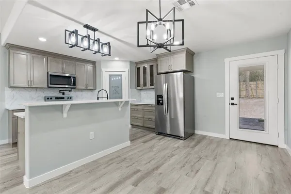 a kitchen with stainless steel appliances granite countertop a refrigerator a stove a microwave oven a sink dishwasher and a refrigerator with wooden floor