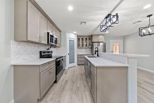 a kitchen with a sink a counter top space stainless steel appliances and cabinets