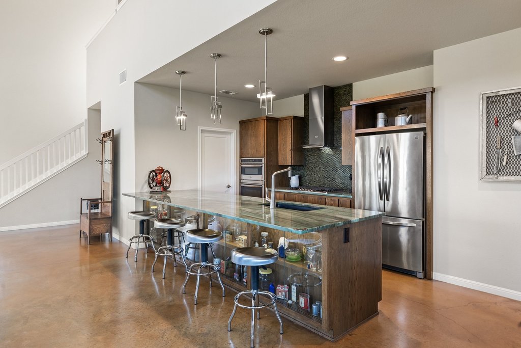 1101 Windy Hills Road Dripping Springs, TX 78620 - Photo 12 of 40 A spacious kitchen with a stunning green marble island and sleek stainless steel appliances anchors this contemporary open-concept living area.