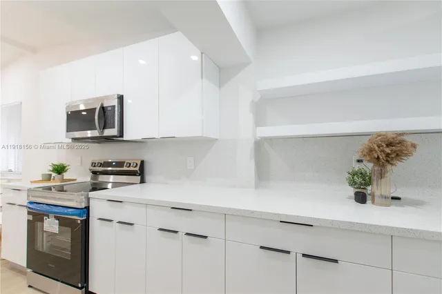 a kitchen with stainless steel appliances a microwave a stove and white cabinets
