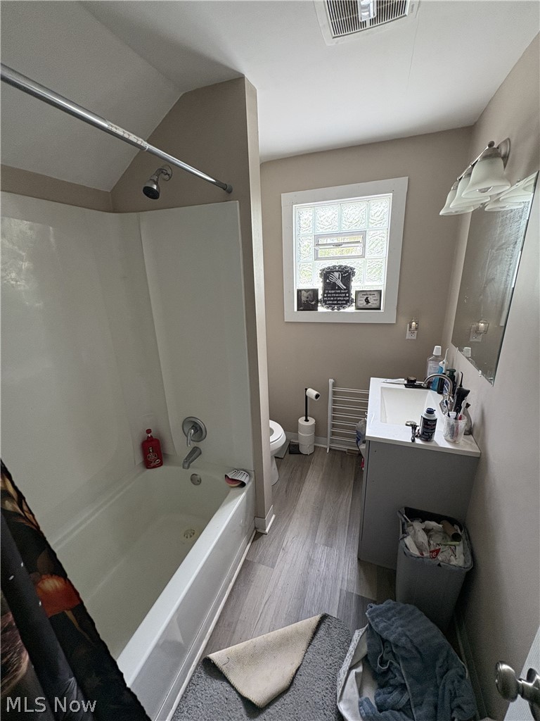 727 Wooster Road North Barberton, OH 44203 - Photo 18 of 37 727 (4-Bed) - Bathroom featuring a white tub with shower, single vanity with white basin, light wood-finish flooring, and a glass block window