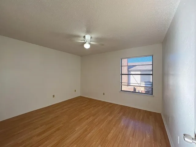 an empty room with wooden floor chandelier fan and windows