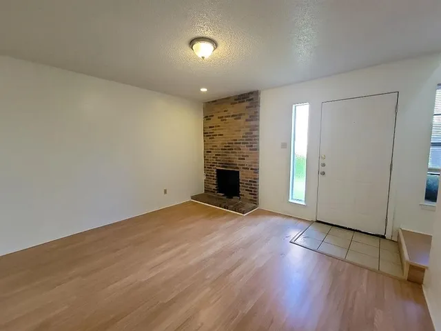 an empty room with wooden floor fireplace and windows
