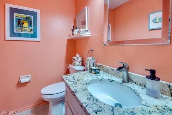 a bathroom with a granite countertop sink mirror vanity and toilet