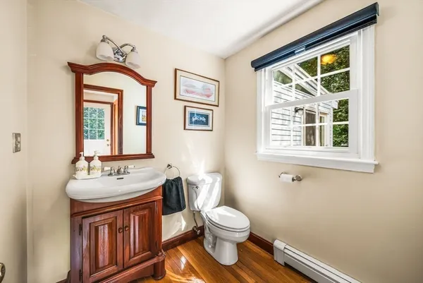 a bathroom with a toilet a sink a mirror and a window