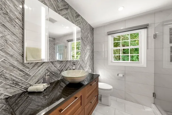a bathroom with a granite countertop sink a toilet and mirror