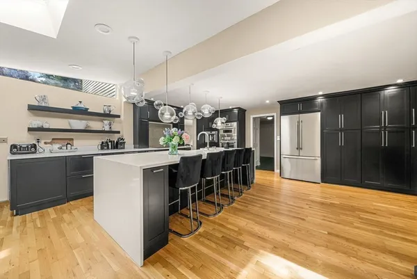 a kitchen with stainless steel appliances kitchen island granite countertop a refrigerator a stove top oven and white cabinets