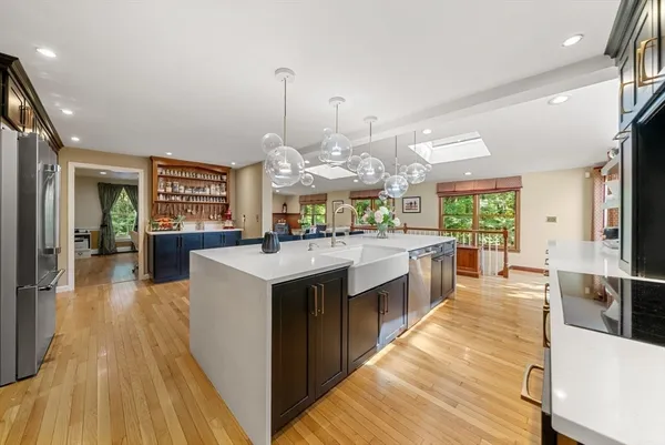 a large kitchen with stainless steel appliances kitchen island granite countertop a large counter top a stove a chimney a sink and a living room view