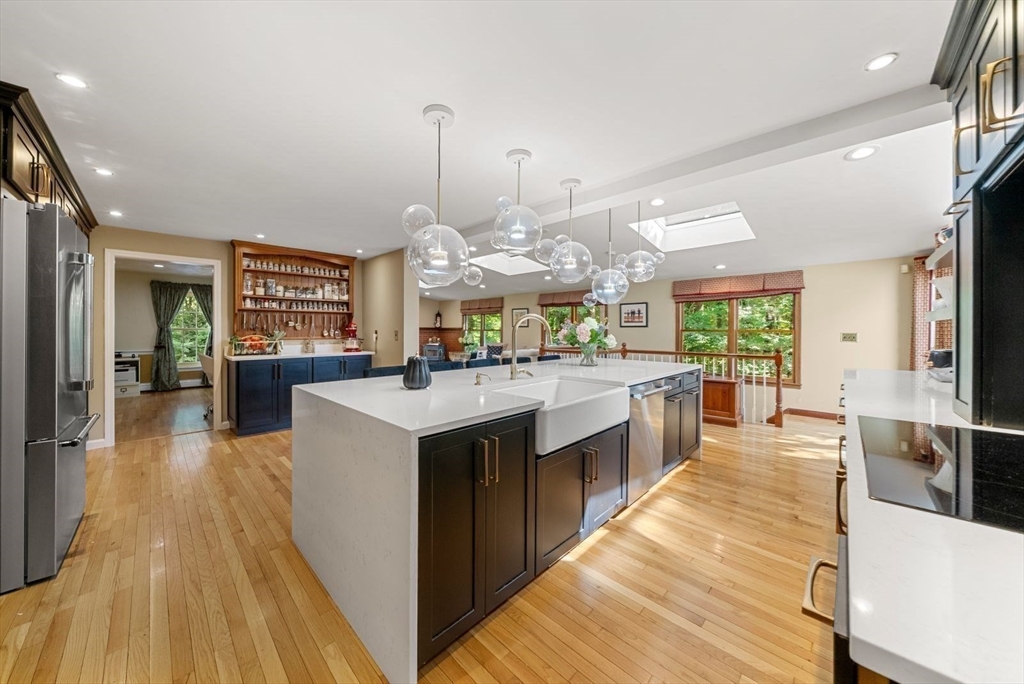 44 Gilmore Road Southborough, MA 01772 - Photo 6 of 40 a large kitchen with stainless steel appliances kitchen island granite countertop a large counter top a stove a chimney a sink and a living room view