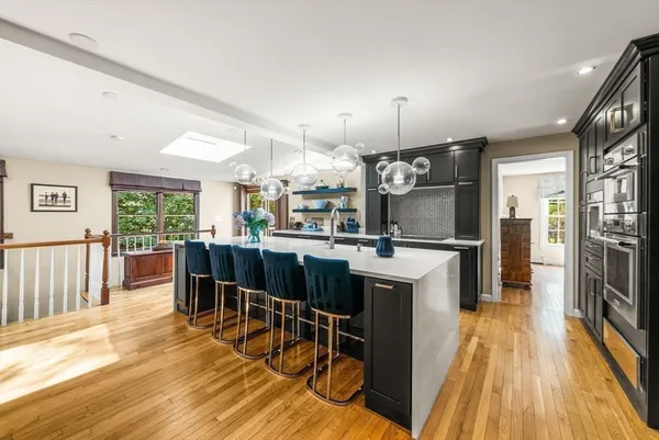 a kitchen with stainless steel appliances kitchen island granite countertop a table chairs and a refrigerator
