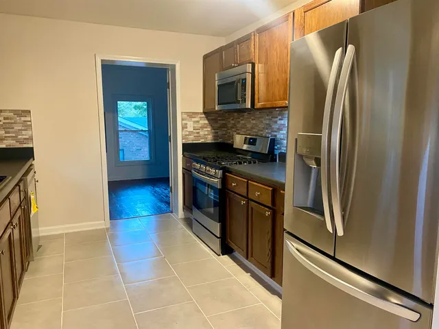 a kitchen with stainless steel appliances granite countertop a refrigerator a stove and a sink