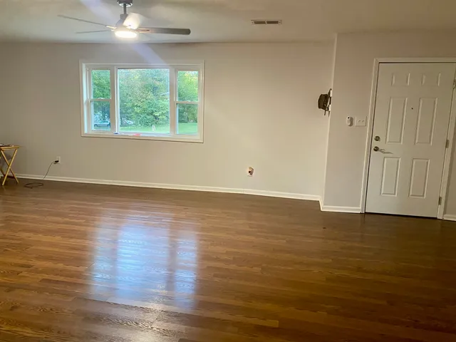 an empty room with wooden floor and windows