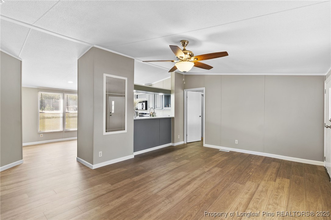 1334 East Green Springs Road Parkton, NC 28371 - Photo 5 of 32 an empty room with wooden floor chandelier fan and windows