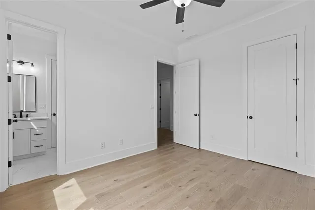 an empty room with wooden floor chandelier fan and windows