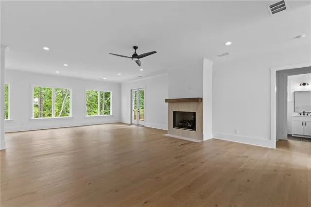 an empty room with wooden floor fireplace and windows