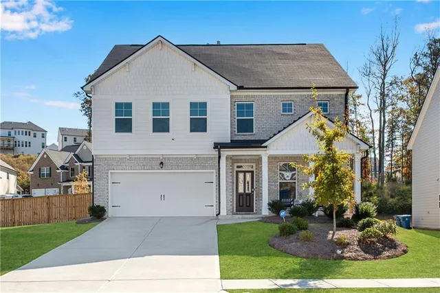 a view of a white house with a small yard and a large tree