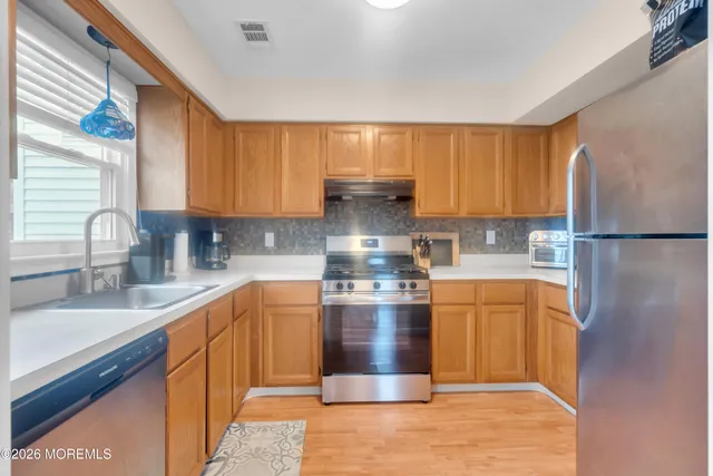 a kitchen with stainless steel appliances granite countertop a refrigerator a sink dishwasher a stove with wooden cabinets