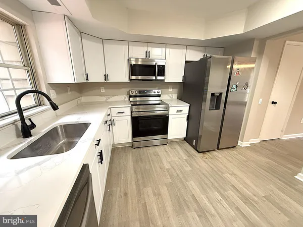 a kitchen with a sink a refrigerator and a stove top oven with wooden floor