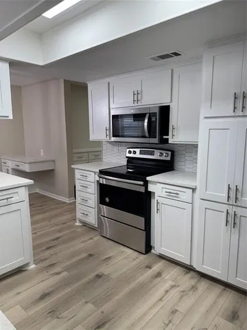 a kitchen with cabinets stainless steel appliances and wooden floor