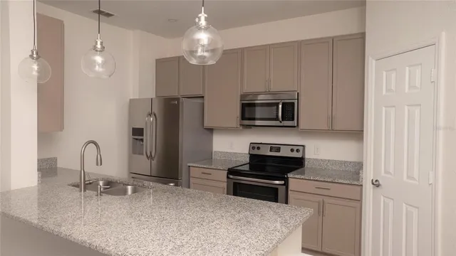 a kitchen with stainless steel appliances granite countertop a refrigerator a stove and a sink with wooden floor