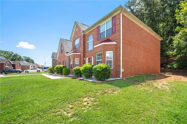 a backyard of a house with plants and large tree