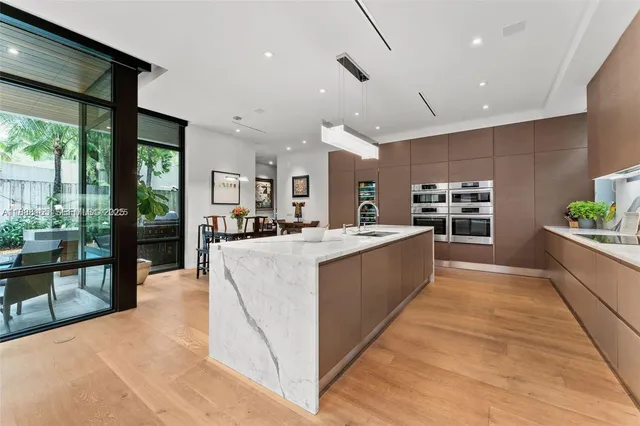 a large kitchen with kitchen island a large counter top space a sink stainless steel appliances and windows