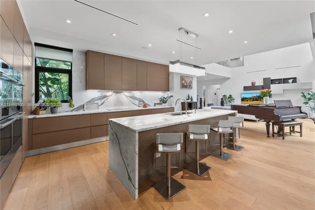 a kitchen with stainless steel appliances kitchen island granite countertop a table chairs sink and cabinets
