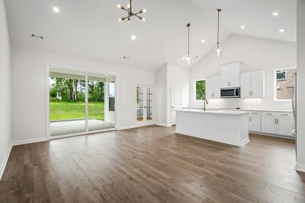 a large kitchen with stainless steel appliances granite countertop a stove a sink dishwasher a refrigerator white cabinets and wooden floor