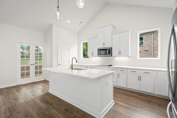 a large white kitchen with granite countertop a stove a sink a window and dining table
