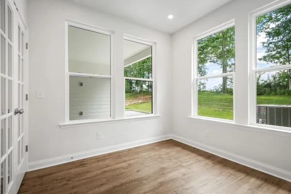 an empty room with wooden floor and windows