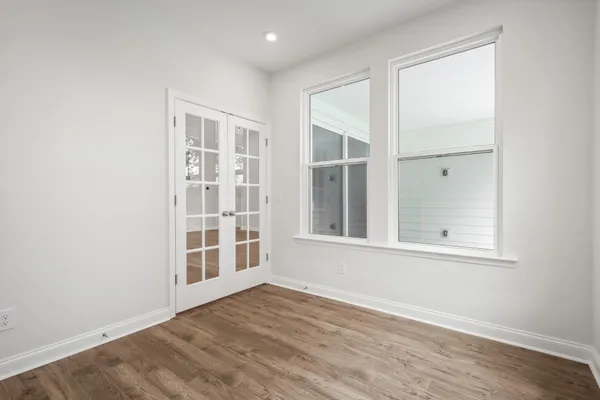 an empty room with wooden floor and windows