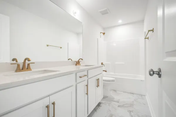 a bathroom with a double vanity sink toilet a shower and a tub