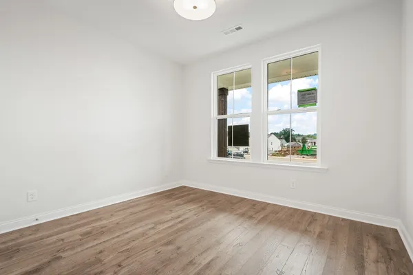 an empty room with wooden floor and windows