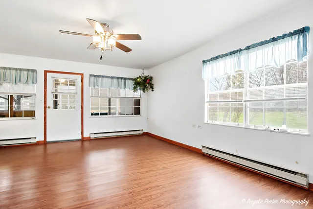 a view of an empty room with a window and wooden floor