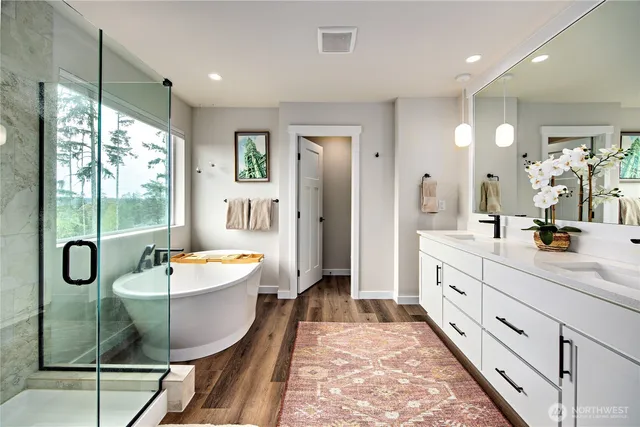 a spacious bathroom with a double vanity sink a mirror a bathtub and shower