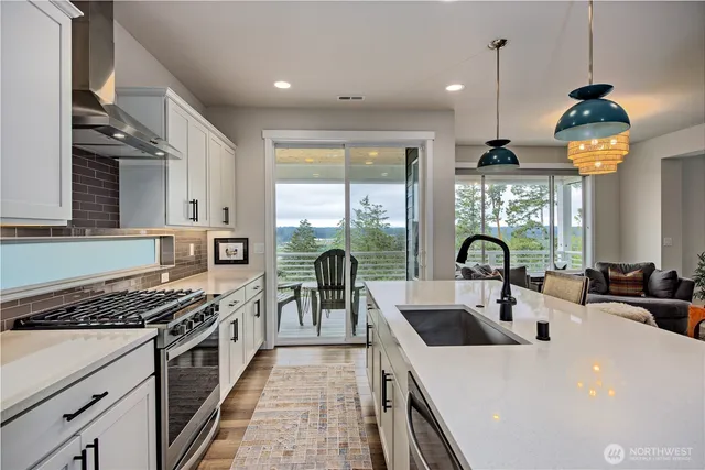 a kitchen with a stove a sink a dining table and chairs with wooden floor