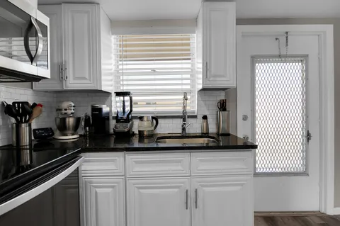 a kitchen with stainless steel appliances granite countertop white cabinets sink and a granite counter top