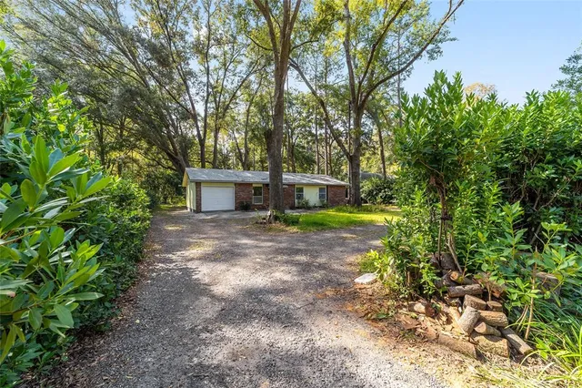 a view of a house with a yard and large trees