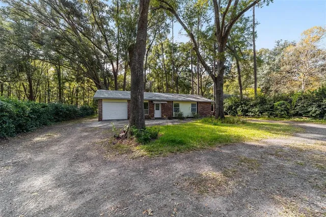 a view of a house with a yard and large tree