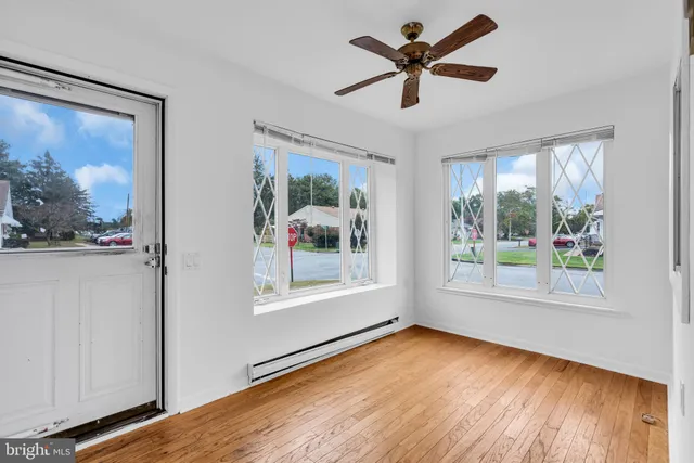 a view of empty room with wooden floor and fan