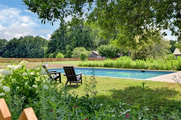 a view of swimming pool with lawn chairs and plants