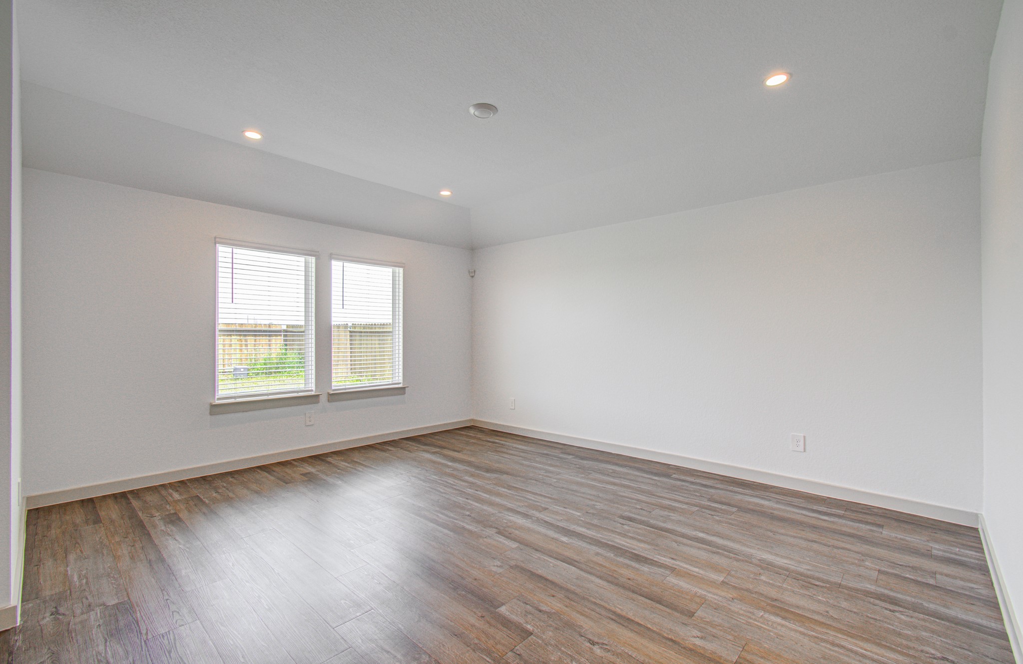 7903 Wrangler Shack Lane Rosharon, TX 77583 - Photo 19 of 29 This bright and spacious room, featuring large windows, recessed lighting, and elegant wood-style flooring, is perfect for creating a cozy living space.