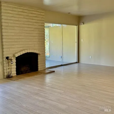 a view of empty room with wooden floor and fireplace