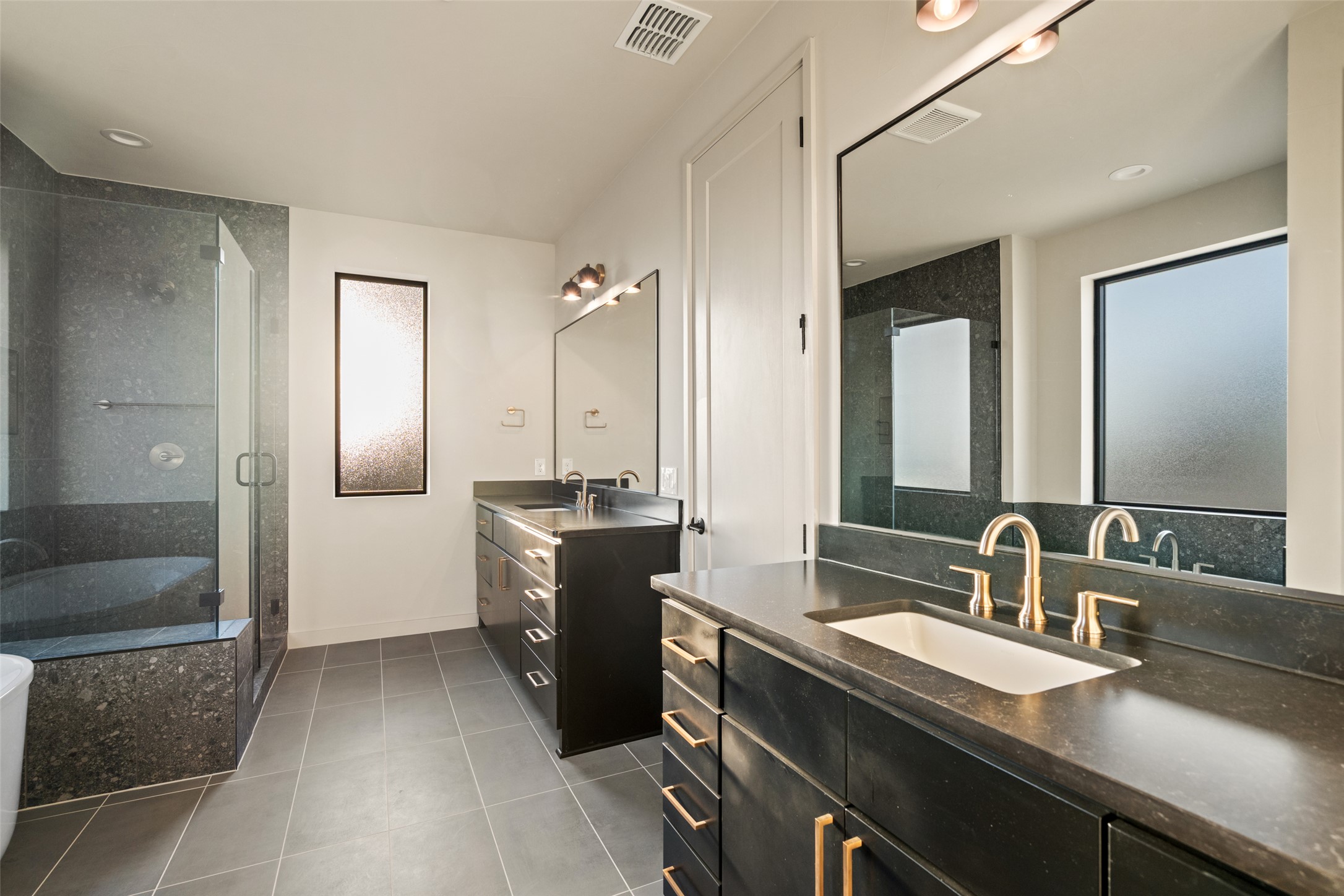 9803 Ribelin Ranch Court, Unit 19 Austin, TX 78750 - Photo 10 of 14 Dual vanities with sophisticated hardware and a frameless glass shower define this contemporary primary bathroom.