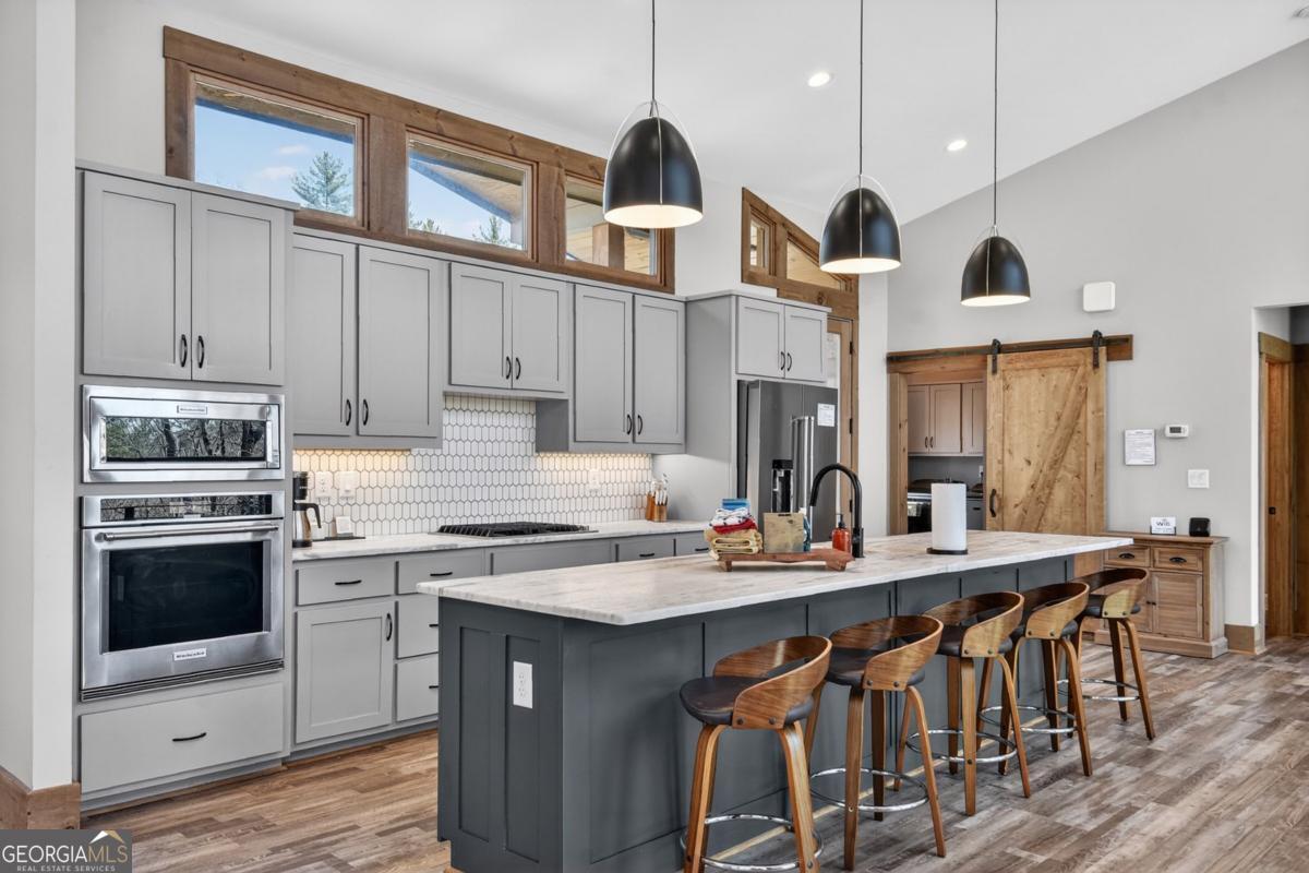 466 Watersong Bluff West Ellijay, GA 30540 - Photo 25 of 67 a kitchen with stainless steel appliances granite countertop a stove a sink dishwasher and a refrigerator with wooden floor